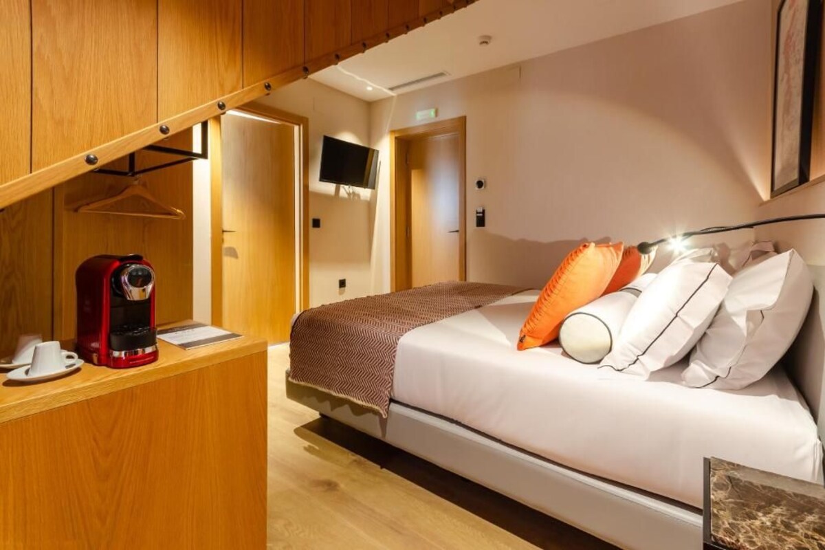 Une chambre d’hôtel équipée d’un lit, d’une machine à café, d’une télévision et d’une armoire en bois.