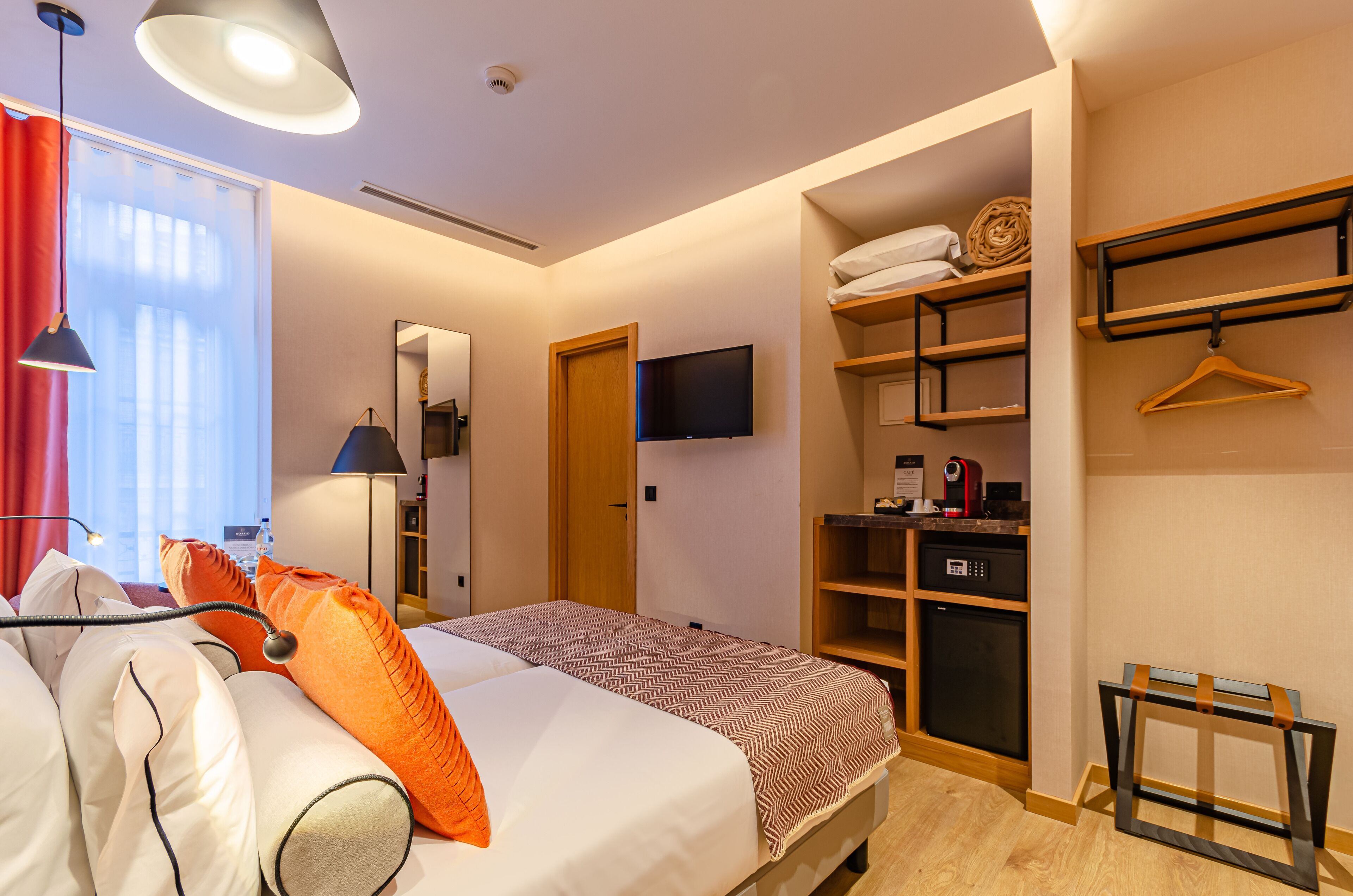 Une chambre d’hôtel équipée d’un lit, d’une télévision, d’une armoire et d’un bureau.