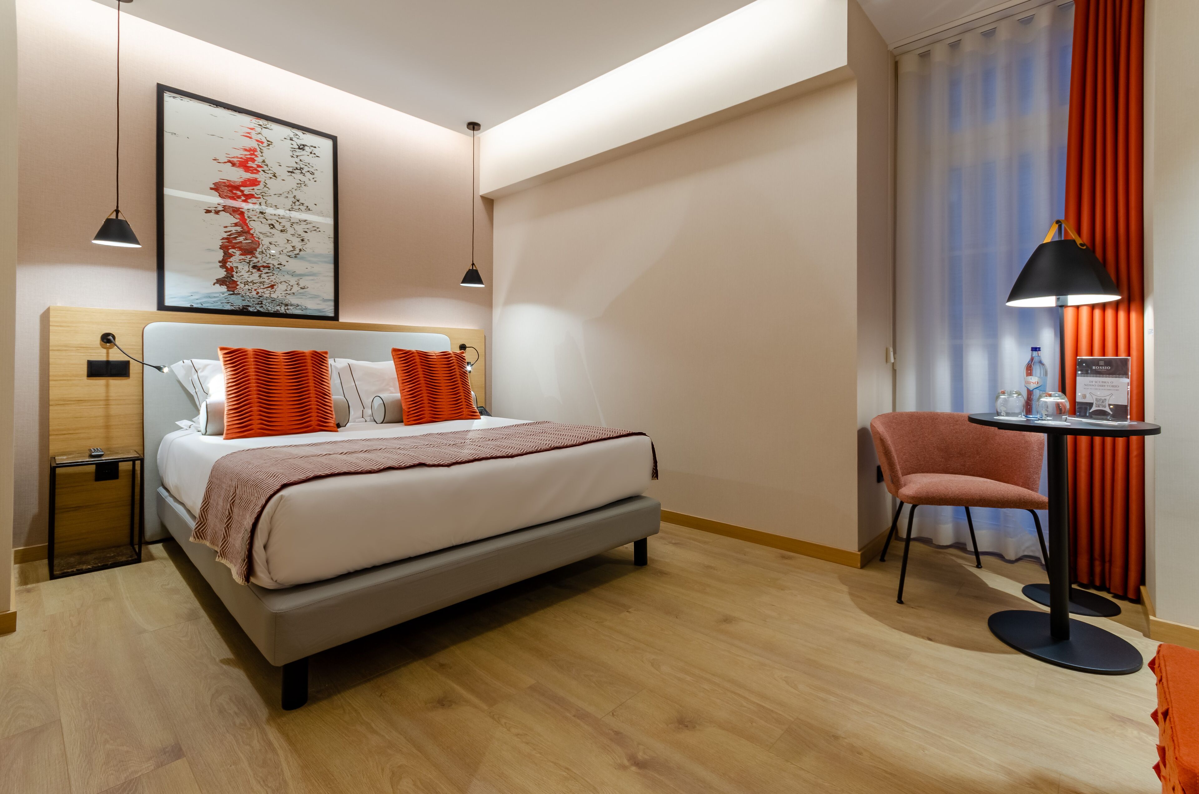 Une chambre d’hôtel moderne équipée d’un lit, d’une table de chevet, d’une chaise et d’un bureau avec une lampe.