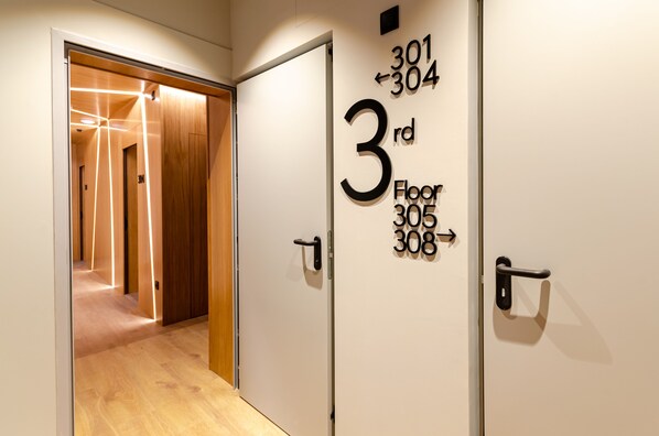 A hallway leading to a door labeled "3rd Floor 305 308" with a wooden floor and a modern design.
