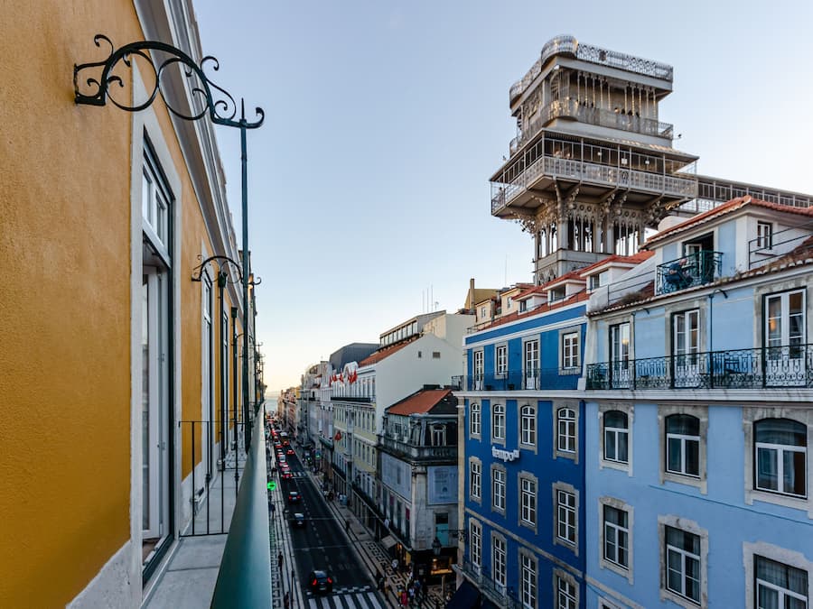 A narrow street with buildings on either side, featuring balconies and a mix of architectural styles.
