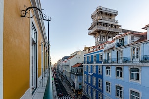 A narrow street with buildings on either side, featuring balconies and a mix of architectural styles.