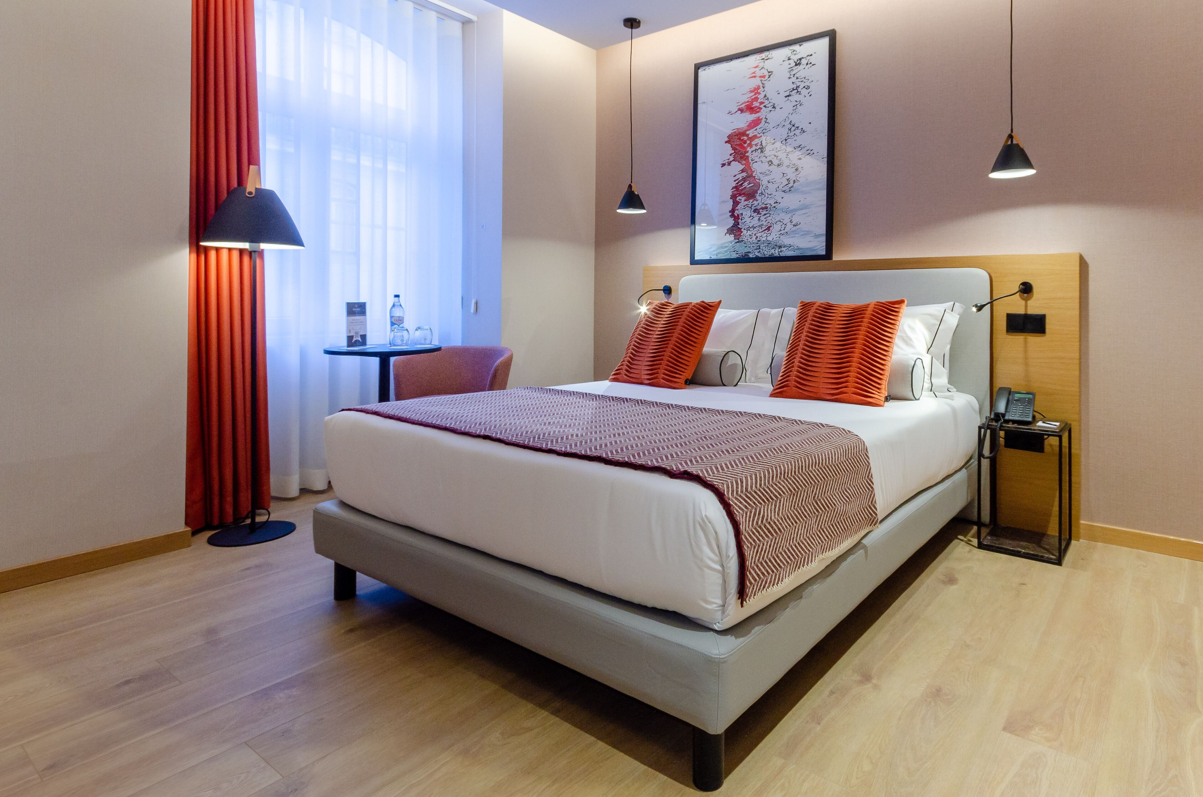 A modern hotel room with a large bed, a desk, and a chair.