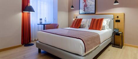 A modern hotel room with a large bed, a desk, and a chair.