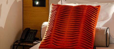 A hotel room with a bed, a bedside phone, and a wall-mounted lamp.