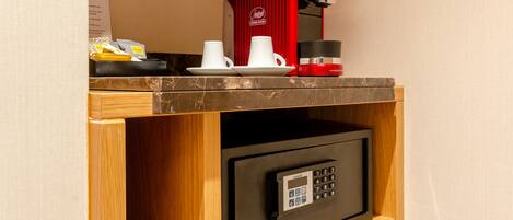 A coffee machine, two cups, and a small safe with a keypad.