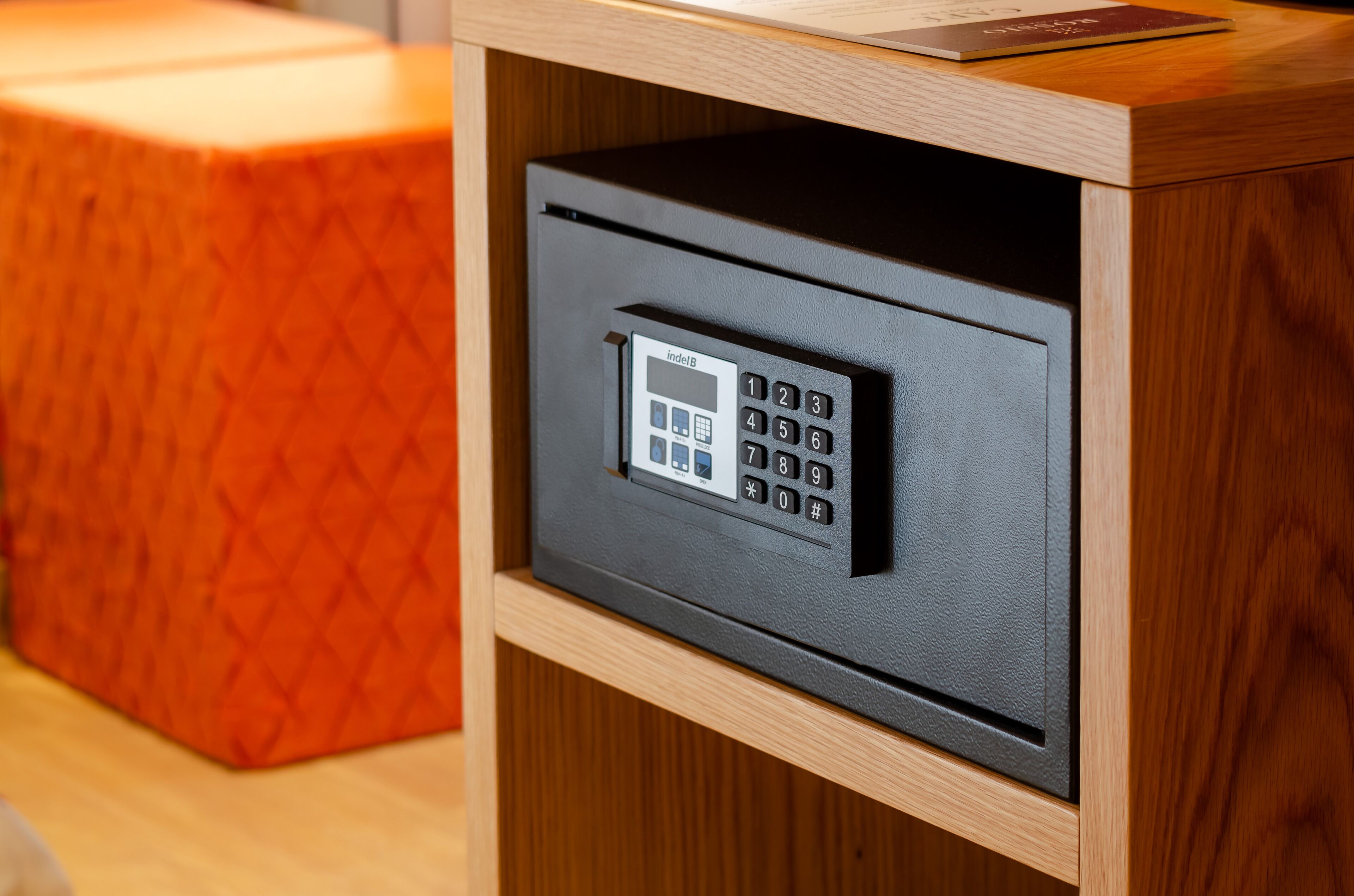 A secure safe with a keypad, located in a wooden cabinet.