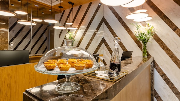 Un espace d’accueil doté d’un comptoir en marbre, d’une vitrine en verre où sont exposées des pâtisseries, et d’un éclairage moderne suspendu au plafond.