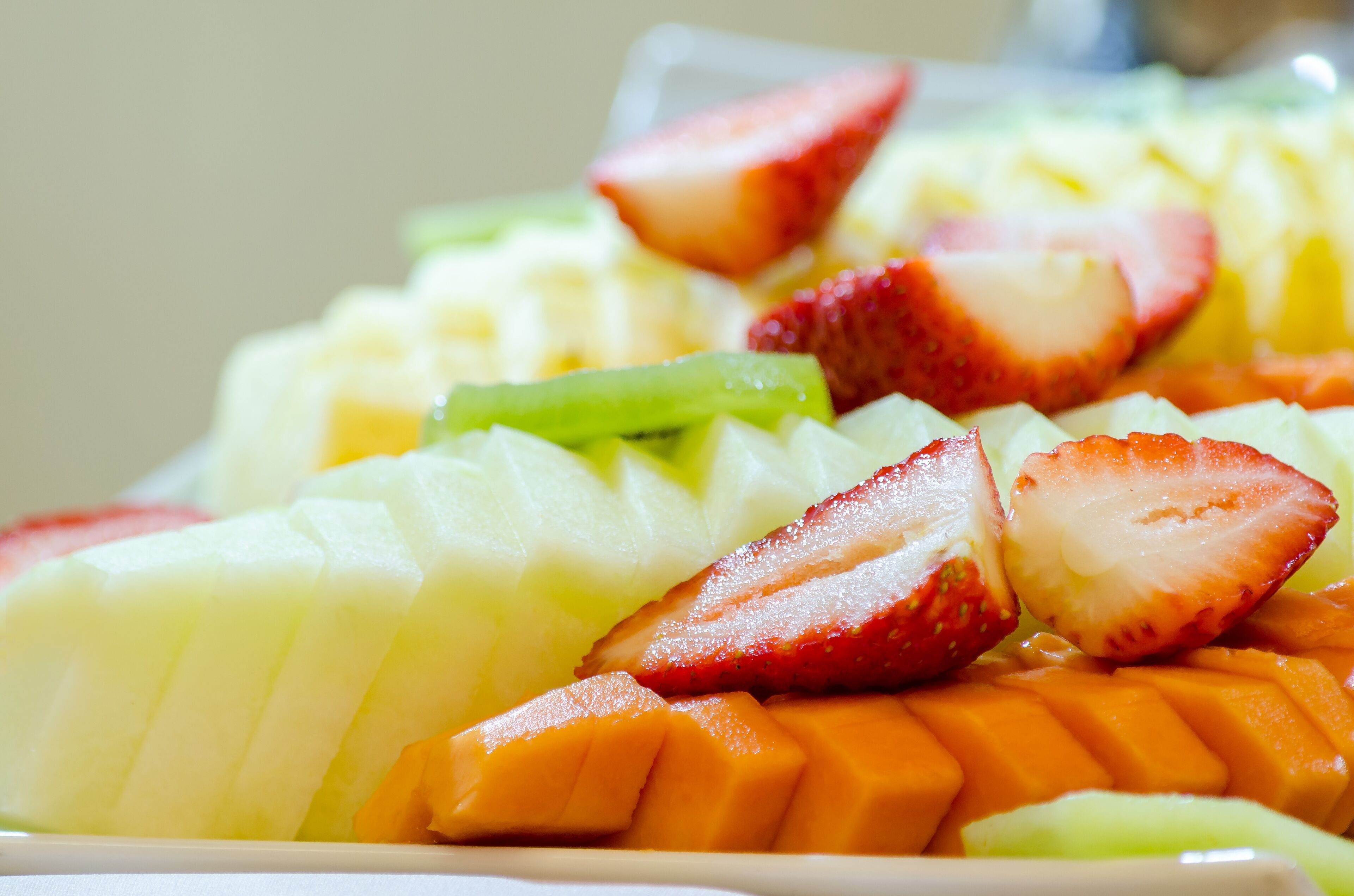 A close-up of a fruit platter with sliced strawberries, melon, and mango.