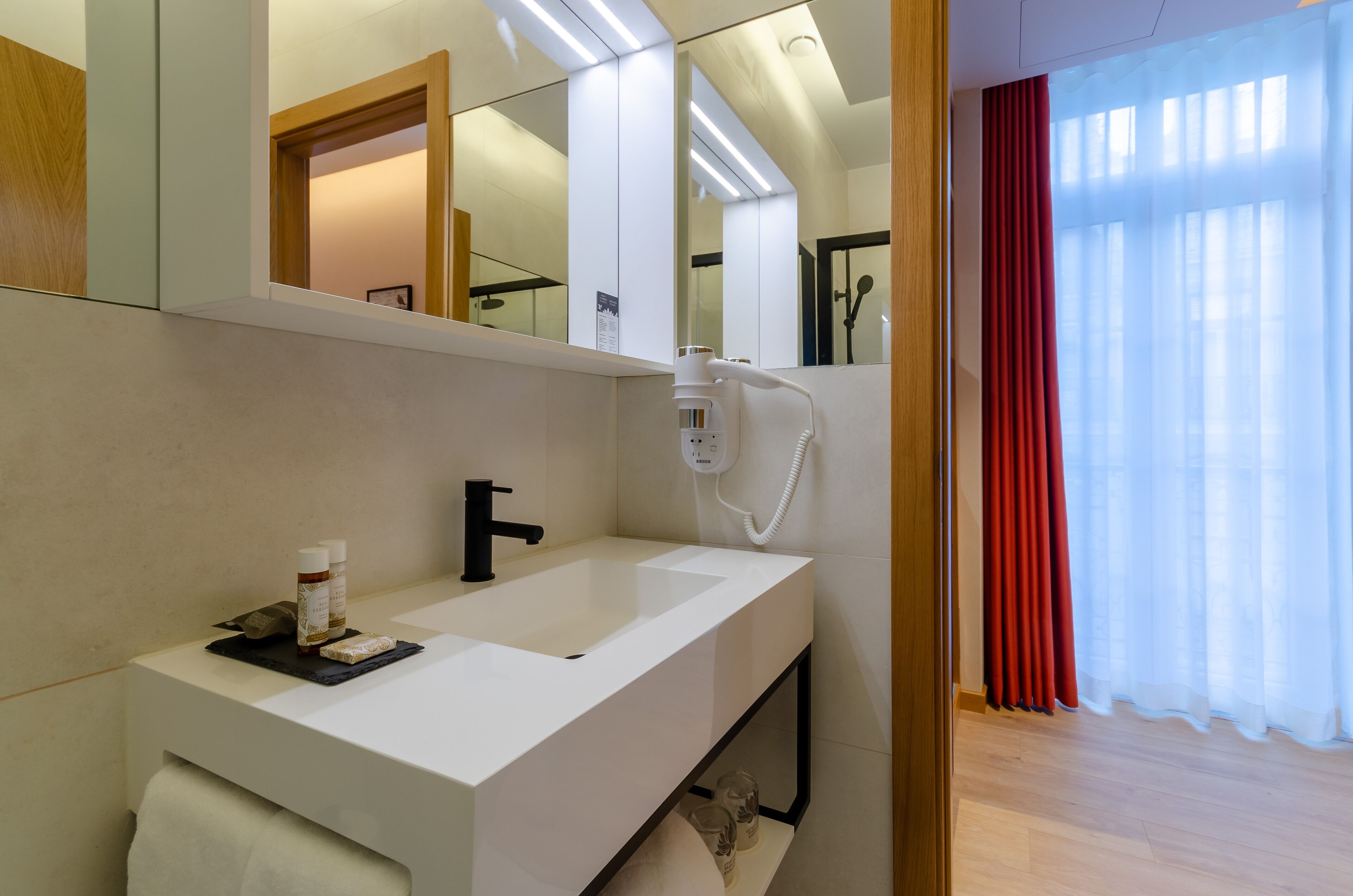 A modern bathroom with a white sink, a mirror, and a hairdryer.