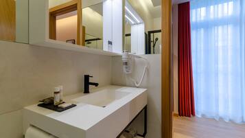 A modern bathroom with a white sink, a mirror, and a hairdryer.