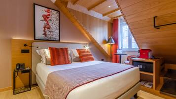 A bedroom with a bed, a nightstand, a lamp, a coffee machine, and a window.