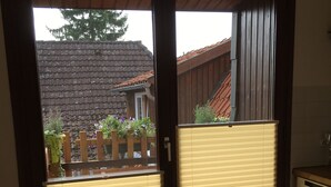 A sliding glass door with a view of a backyard, a wooden fence, and a house with a tiled roof.