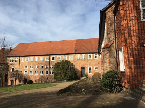 A large brick building with a red-tiled roof, multiple windows, and a central entrance.