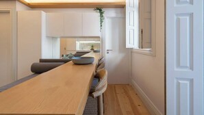 A modern kitchen with white cabinets, a wooden dining table, and a built-in bench.