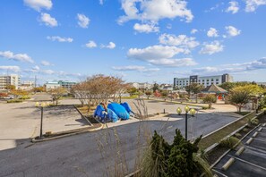 Un parking avec des véhicules à l’abri, un bâtiment avec une enseigne et un ciel dégagé.
