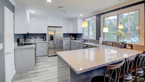 Uma cozinha moderna com uma ilha grande, eletrodomésticos de aço inoxidável e iluminação pendente.
