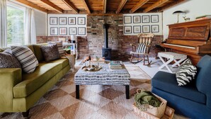 A cozy living room with a brick fireplace, a green sofa, a blue sofa, and a patterned ottoman. - Berkshires / Great Barrington Chic & Cozy, Sleeps 10 (Great Barrington)