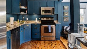 A modern kitchen with blue cabinets, stainless steel appliances, and a wooden floor. - Berkshires / Great Barrington Chic & Cozy, Sleeps 10 (Great Barrington)