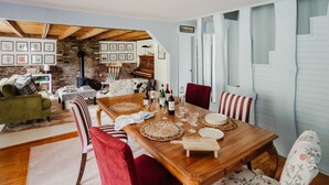 A dining area with a wooden table, red and floral chairs, and a brick wall with framed pictures. - Berkshires / Great Barrington Chic & Cozy, Sleeps 10 (Great Barrington)