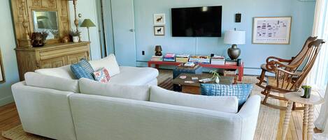 A living room with a sofa, a wooden sideboard, a television, and a rocking chair.