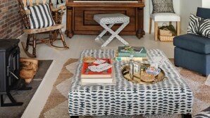 A cozy living room with a wooden piano, a rocking chair, a patterned ottoman, and a blue sofa. - Berkshires / Great Barrington Chic & Cozy, Sleeps 10 (Great Barrington)
