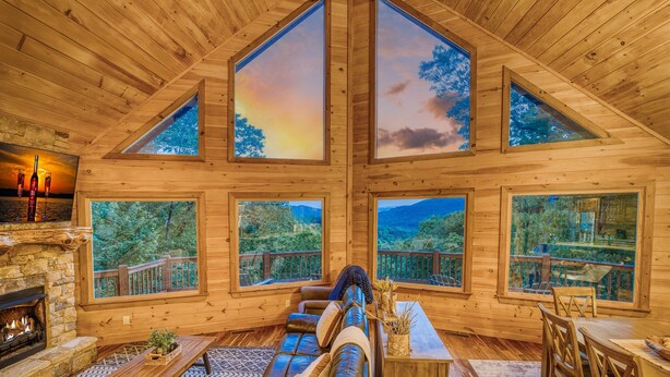 A cozy cabin interior with a fireplace, leather sofa, and large windows offering scenic views. - Endless Views, Secluded Cabin Hot Tub & Fireplaces (Blue Ridge)