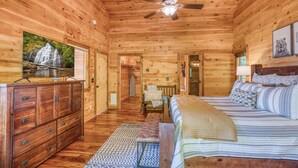A wooden cabin interior with a bed, dresser, ceiling fan, and a painting of a waterfall. - Endless Views, Secluded Cabin Hot Tub & Fireplaces (Blue Ridge)