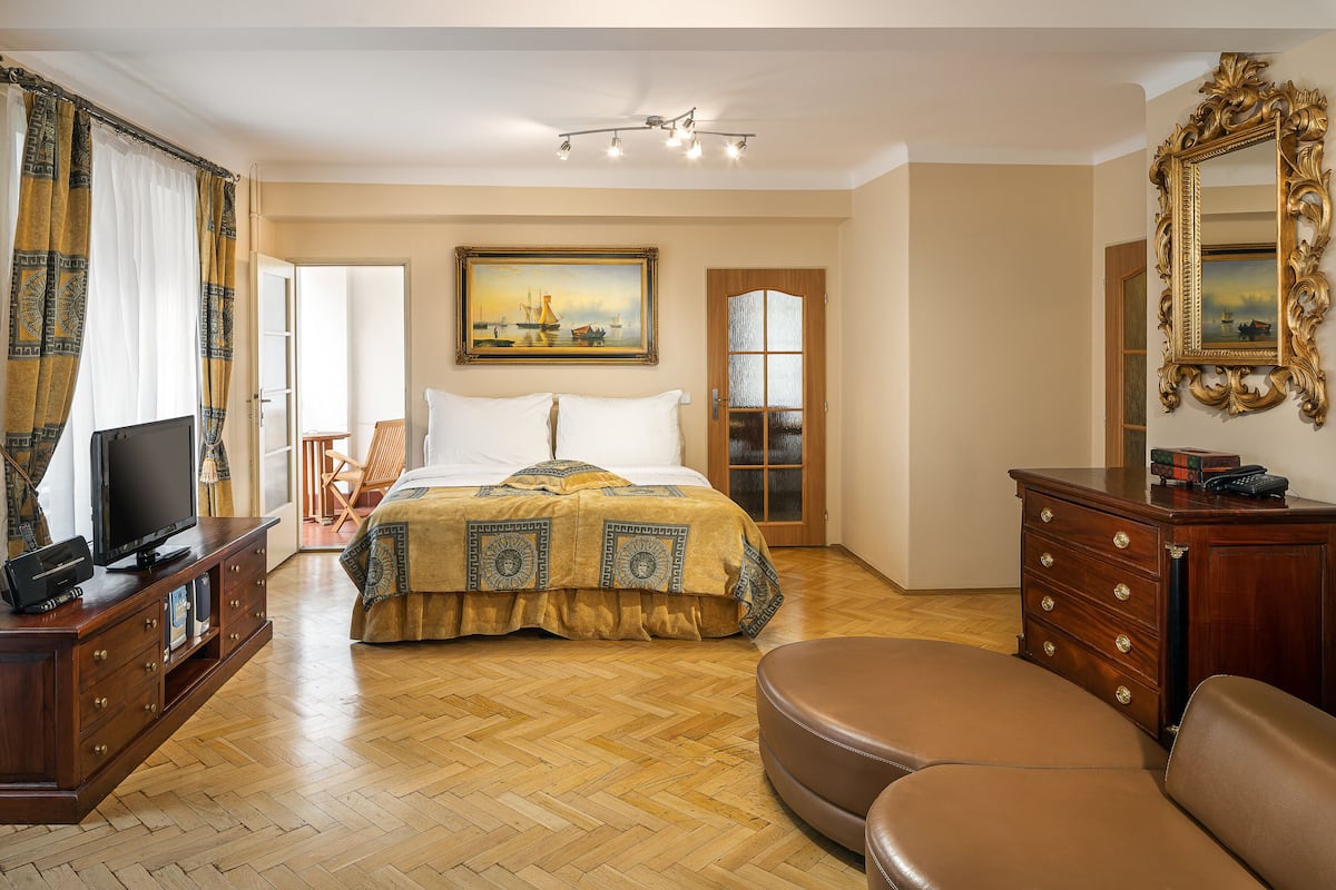 Habitación de hotel con cama, televisión, cómoda, silla y un cuadro en la pared.