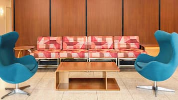 Un hall d’entrée moderne avec un ensemble de canapés et deux fauteuils bleus, une table basse en bois et un mur en bois.