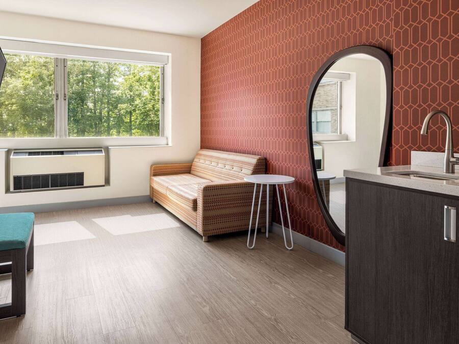 A modern bathroom with a sofa, a round table, a large mirror, and a sink.