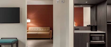 A hotel room with a bed, a small table, a sofa, a microwave, and a TV.