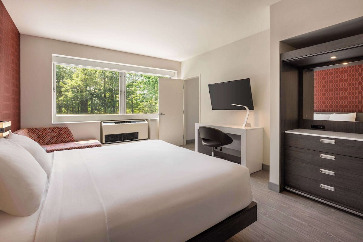 Une chambre d’hôtel moderne équipée d’un grand lit, d’un bureau, d’une télévision et d’une armoire.