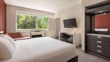 Een moderne hotelkamer met een groot bed, een bureau, een televisie en een kledingkast.