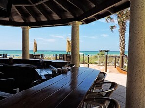 Enjoy ocean views from this outdoor dining area, featuring comfortable seating and shade under a pergola.