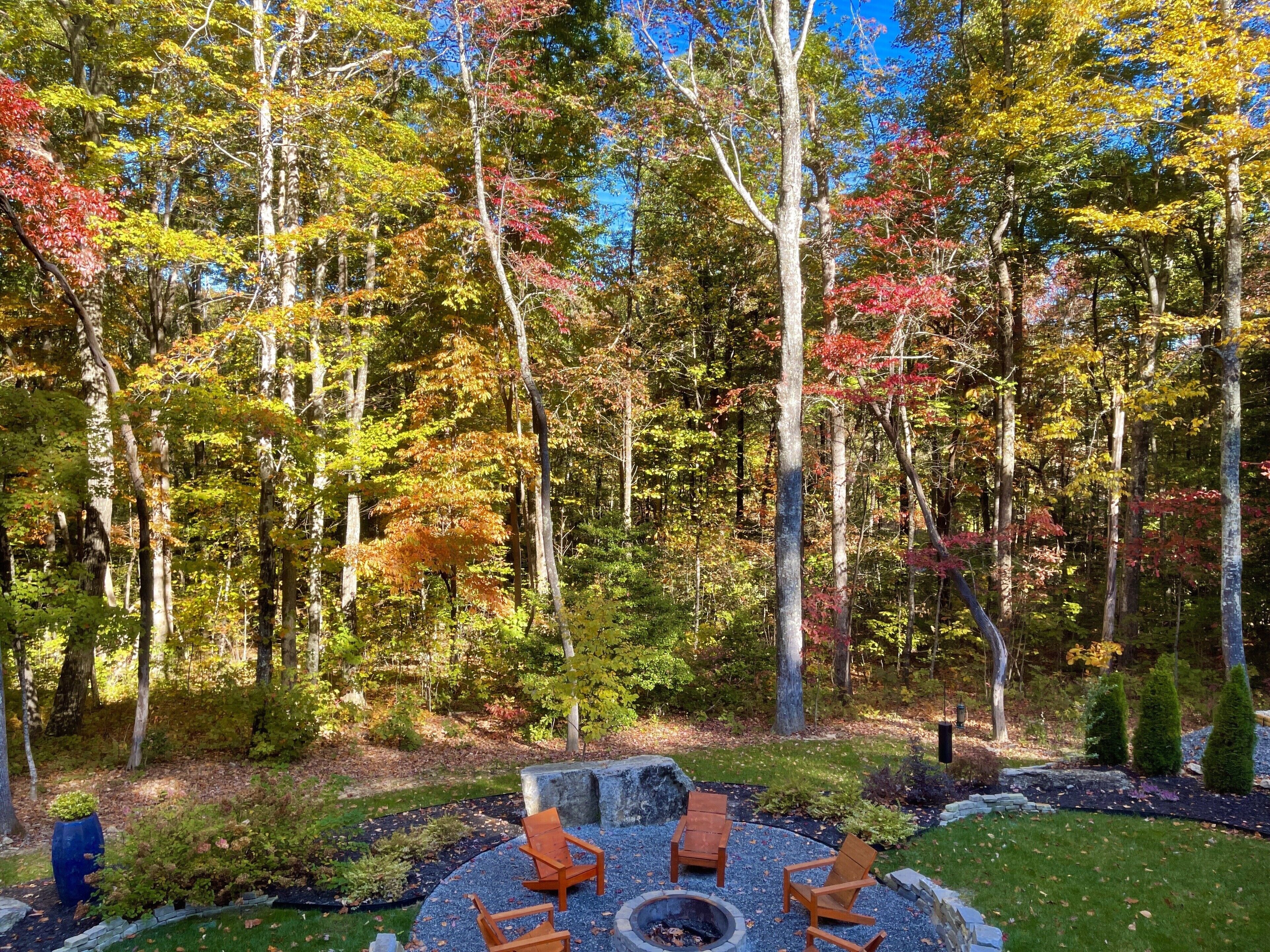 A circular outdoor seating area with a fire pit, surrounded by a gravel path and a grassy lawn.