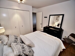 Un dormitorio con cama, cómoda, espejo y una silla.