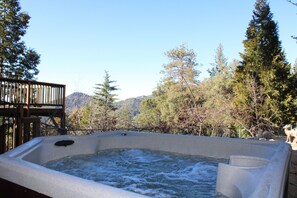 Un jacuzzi con muelle de madera y montañas al fondo.