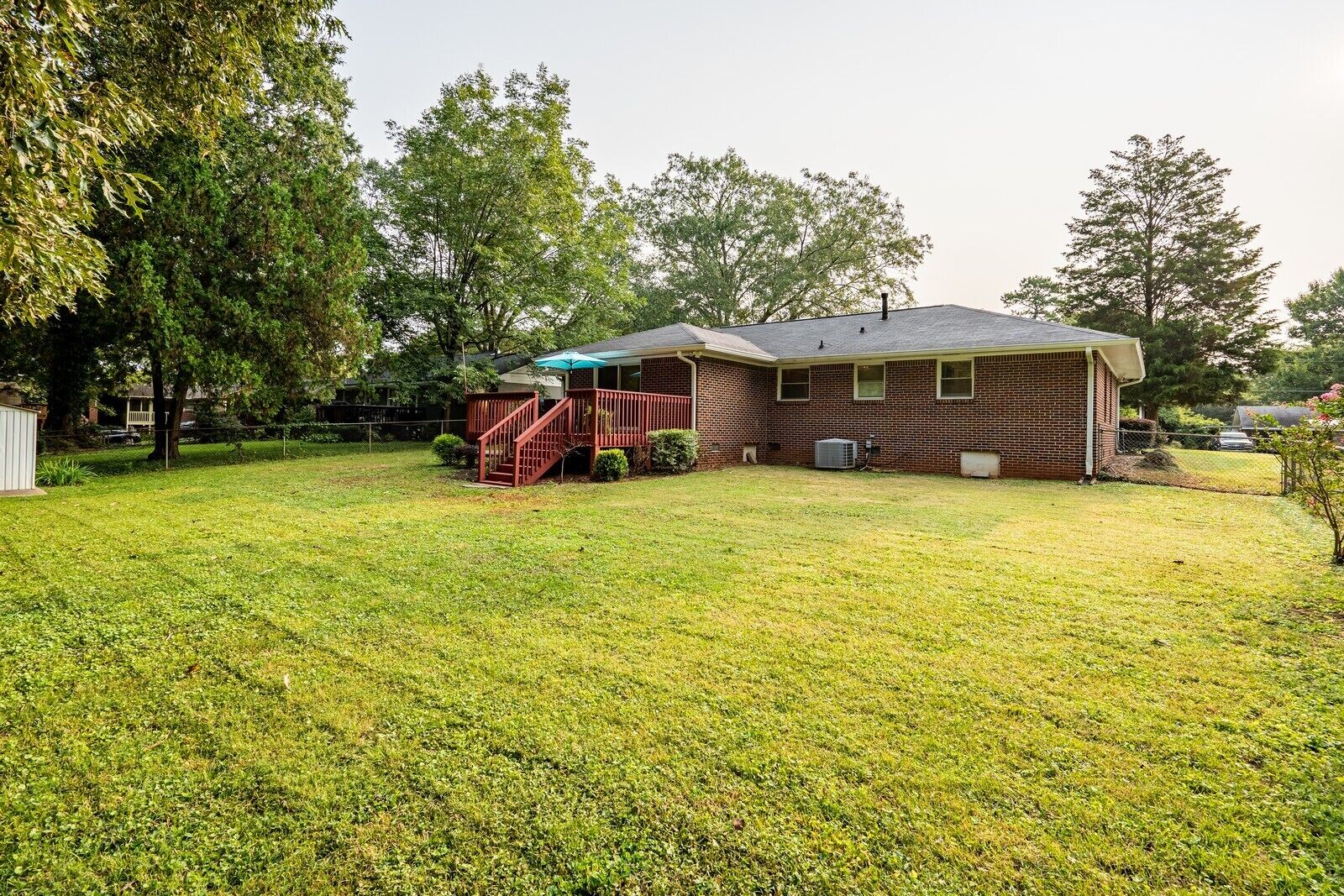A single-story brick house with a covered porch and a small staircase leading to a deck.