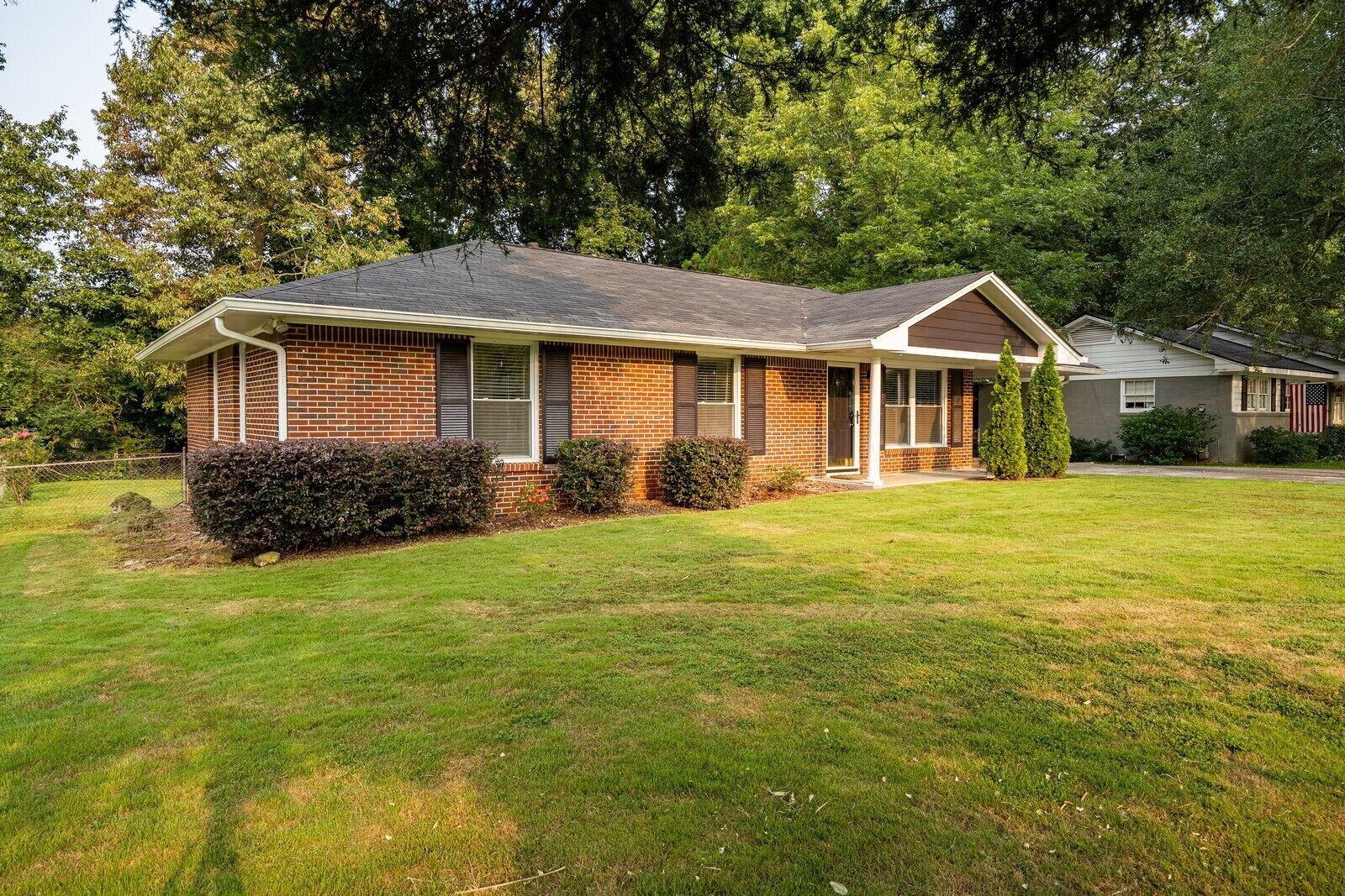 A single-story brick house with a gabled roof, a front porch, and a well-maintained lawn.