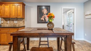 A dining area with a wooden table, chairs, a vase with flowers, and a framed picture on the wall. - Discover Your Beautiful Dream Vacation Rental at The Battery - Truist Park!  (Smyrna)