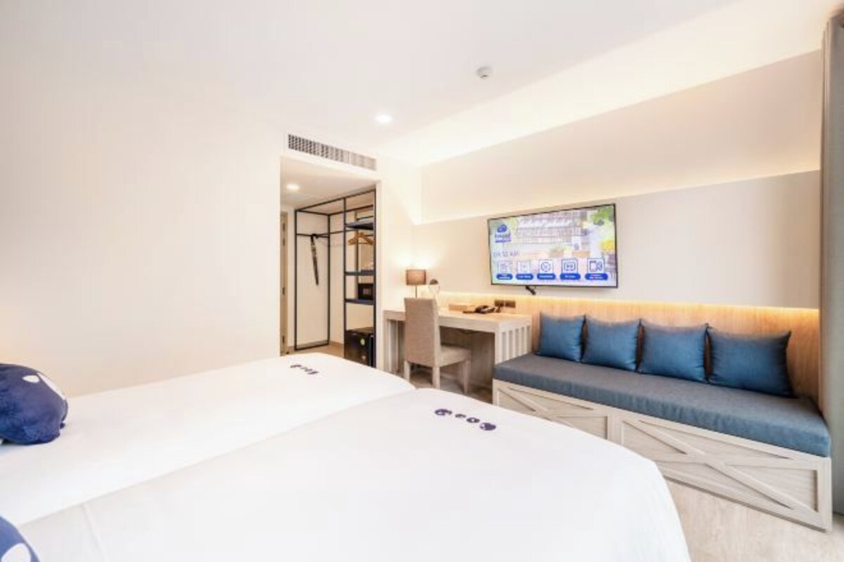 Una habitación de hotel con una cama, un escritorio, una silla y un sofá.