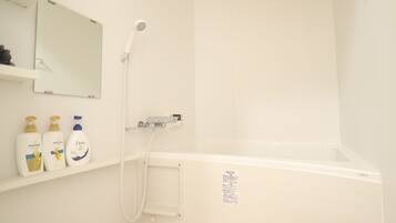 A bathroom with a white bathtub, a showerhead, and a shelf with three bottles of Dove body wash.