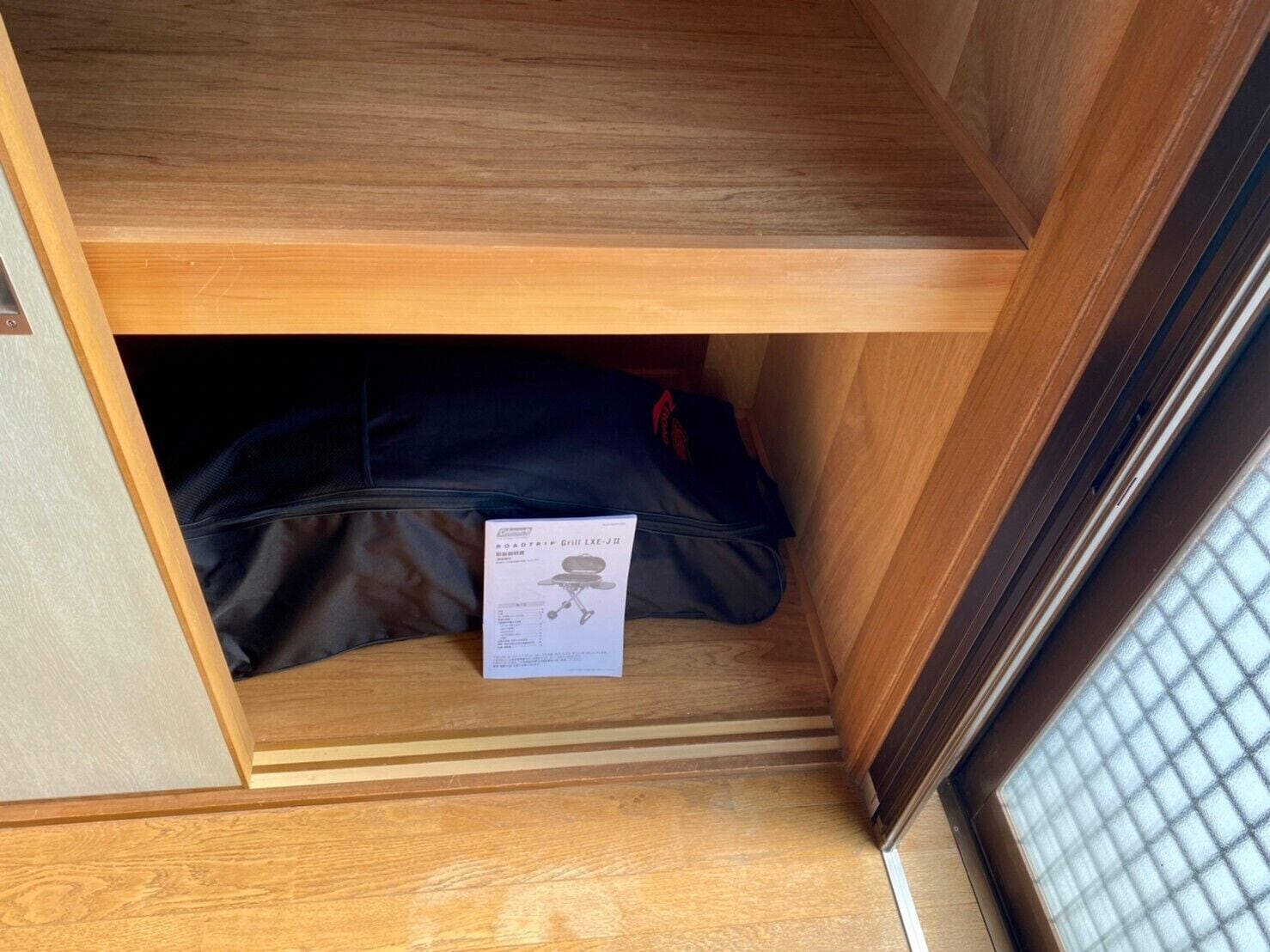 A wooden cabinet with a black bag and a document inside.