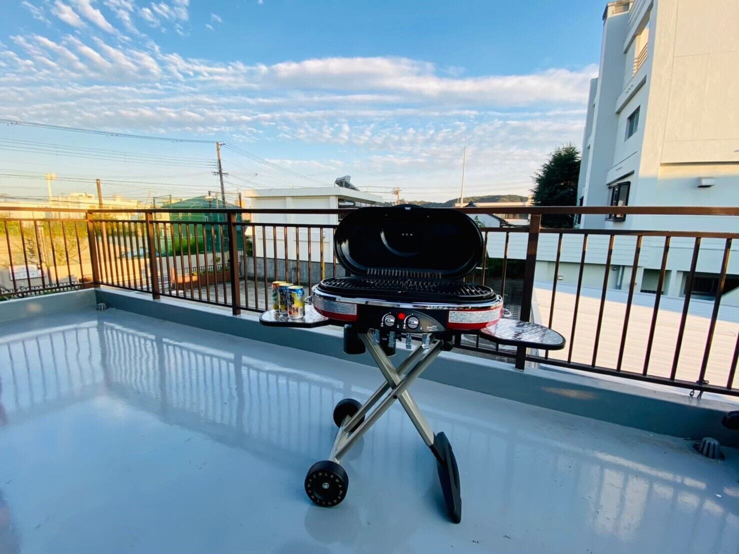 A rooftop with a barbecue grill, a small table, and a railing.