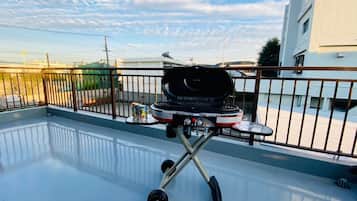 A rooftop with a barbecue grill, a small table, and a railing.