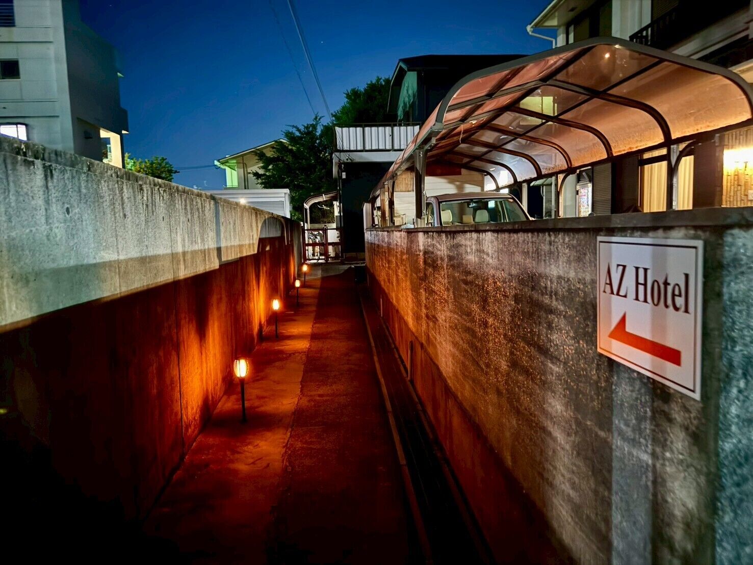 A corridor with a sign for the AZ Hotel, a covered walkway, and a building in the background.