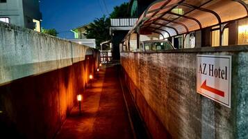 A corridor with a sign for the AZ Hotel, a covered walkway, and a building in the background.