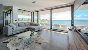 A modern living room with a large glass door leading to a balcony overlooking the sea. - Jimmys Beach Privlaka: Penthouse dream, right by the sea and heated pool (Privlaka)