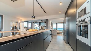A modern kitchen with a large island, stainless steel appliances, and a view to the outside. - Jimmys Beach Privlaka: Penthouse dream, right by the sea and heated pool (Privlaka)